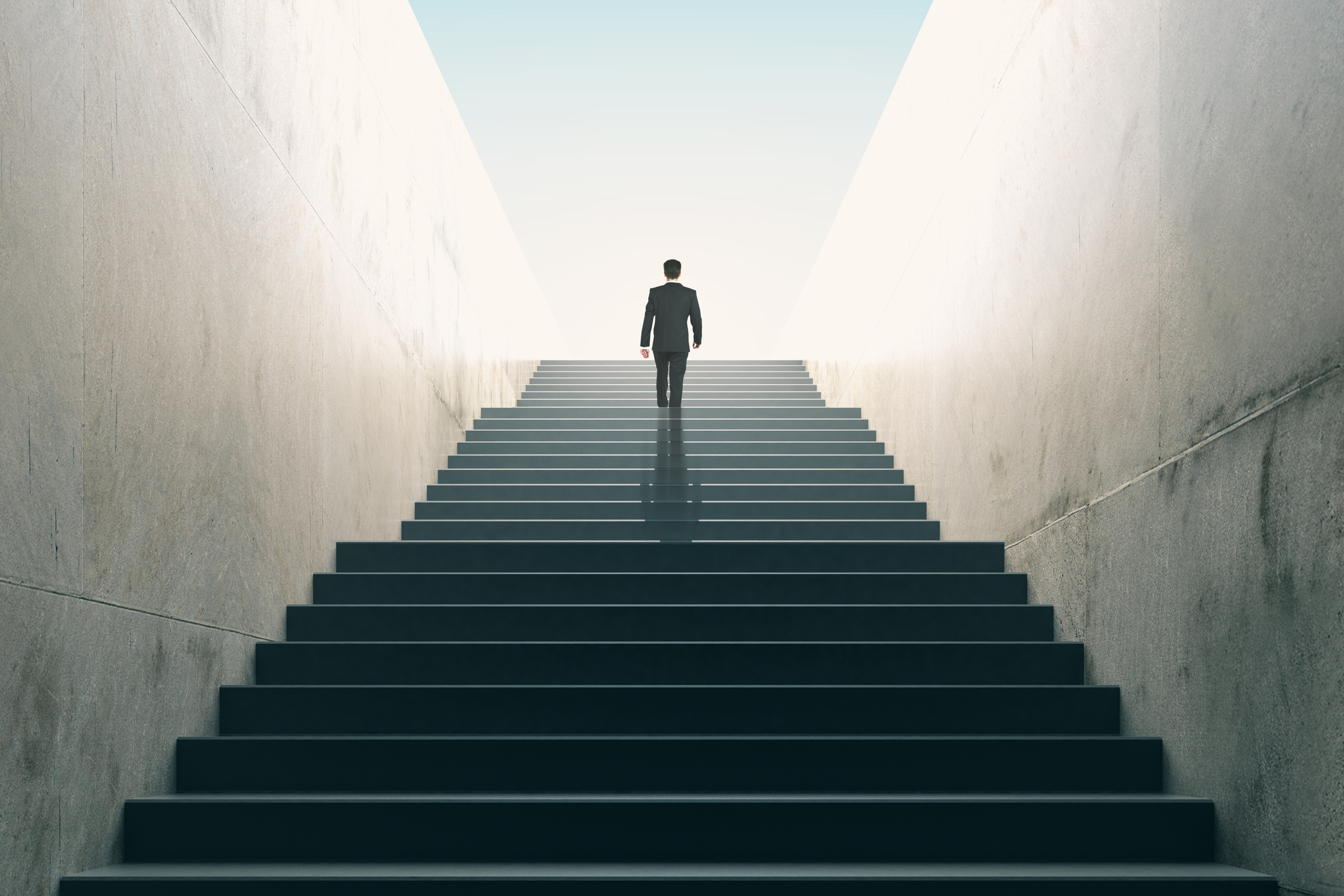 A professional walking up a stairwell toward the light — the search for hard-to-find specialist talent