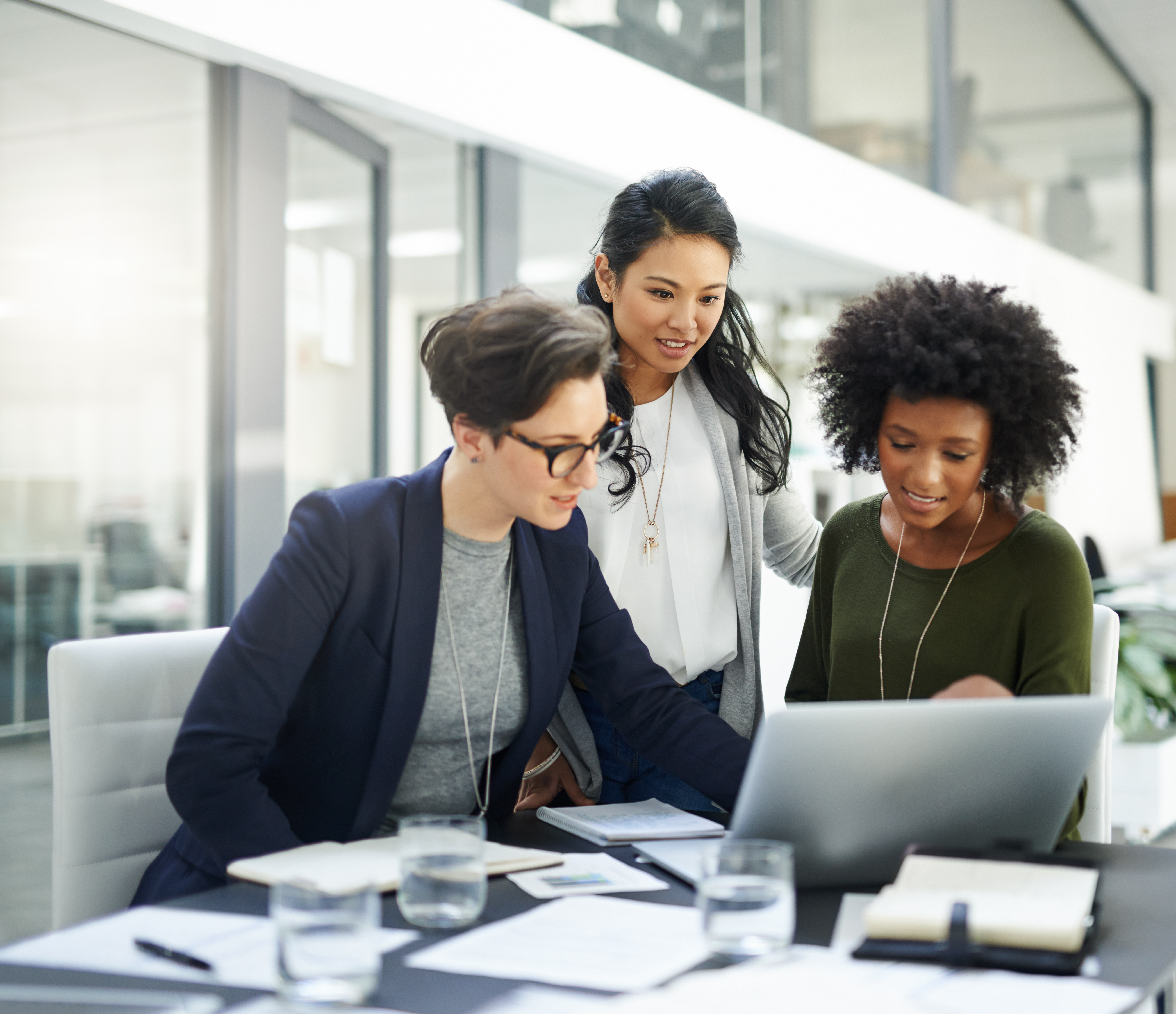 Three colleagues collaborating around a laptop — candidate photo for Colibrí Talent
